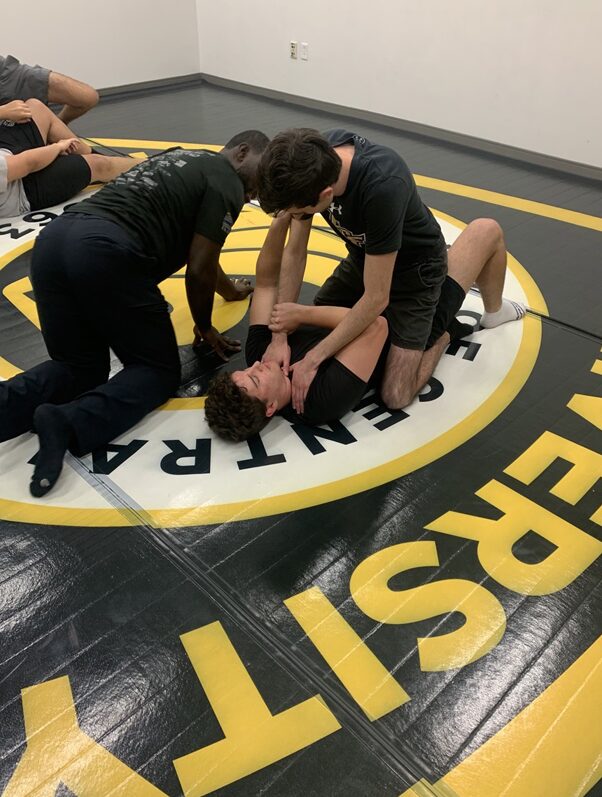 Two explorers demonstrating a defensive tactics on the floor while a third explorer watches