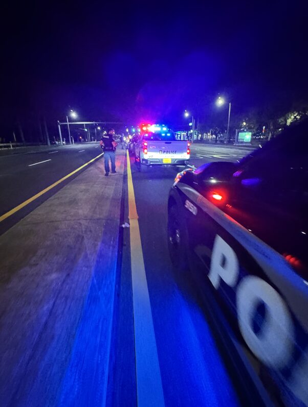 A police officer and an explorer pulling over a vehicle at night.